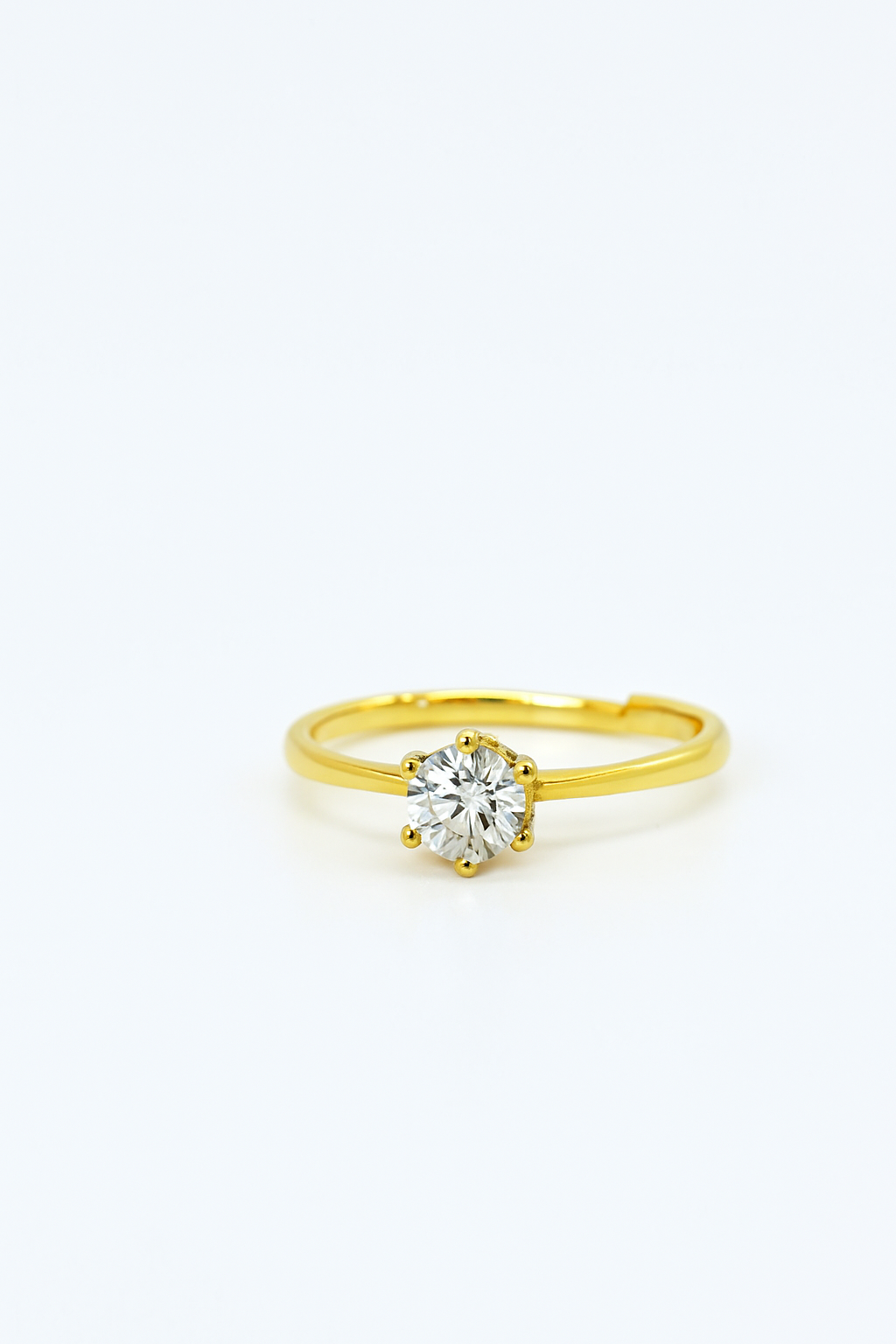 Gold solitaire diamond ring with six-prong setting on white background