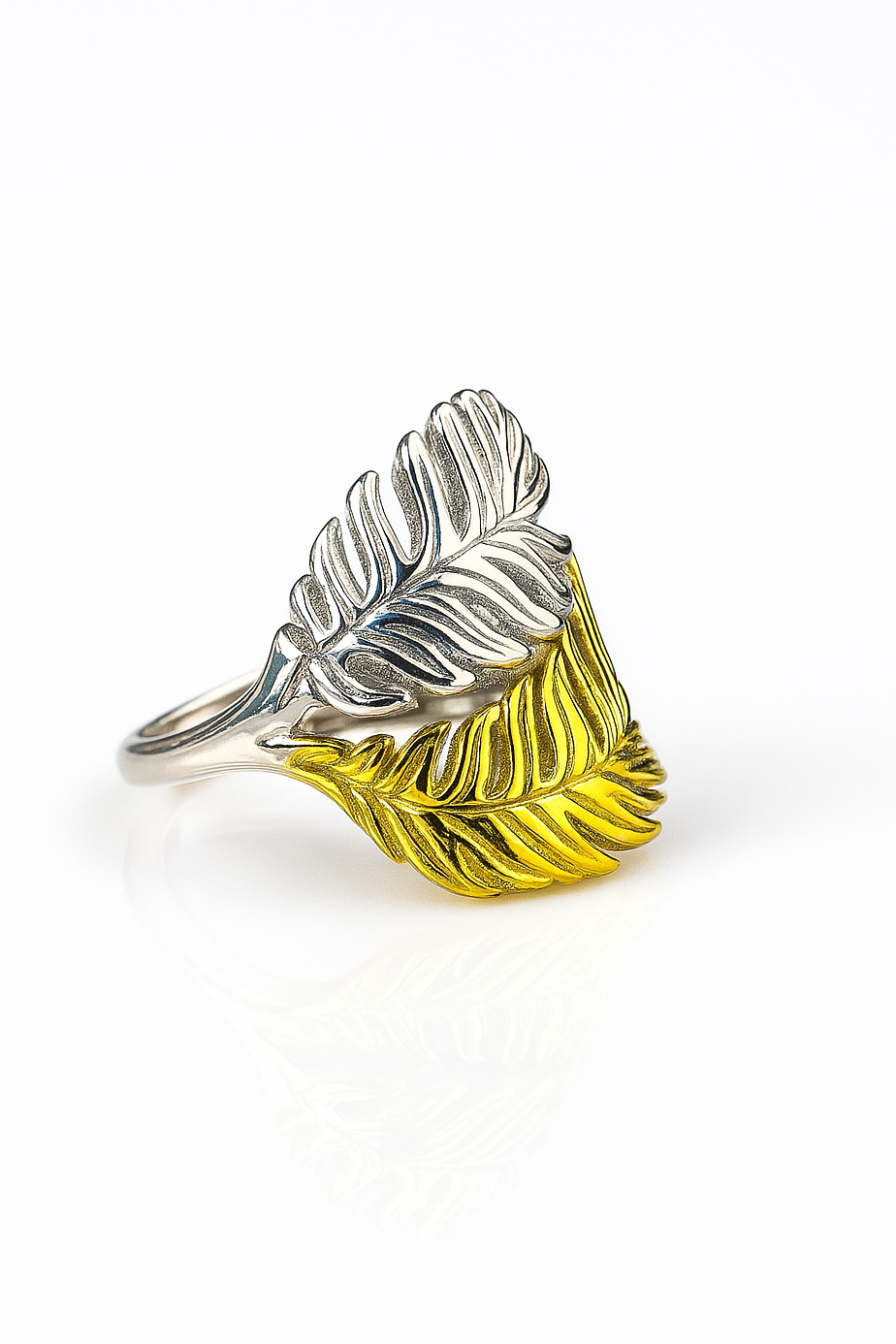 Silver and gold feather-shaped ring on a white background